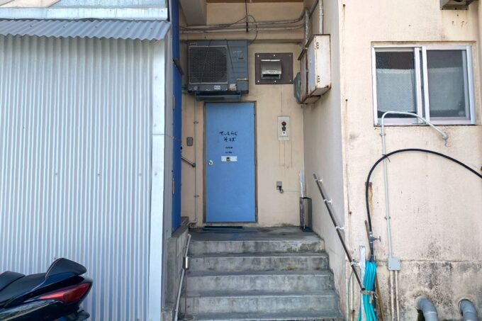 那覇市首里「てぃしらじそば」の現在の入り口は建物横の青いドアだ