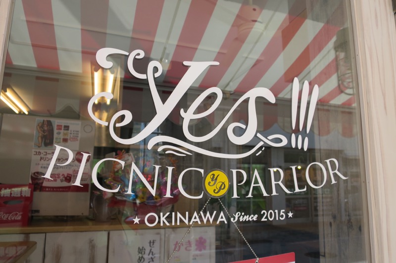 那覇市安謝「Yes!!!PICNIC PARLOR（イエス!!!ピクニックパーラー）」入り口のガラスにもお店のかわいいロゴが描かれている