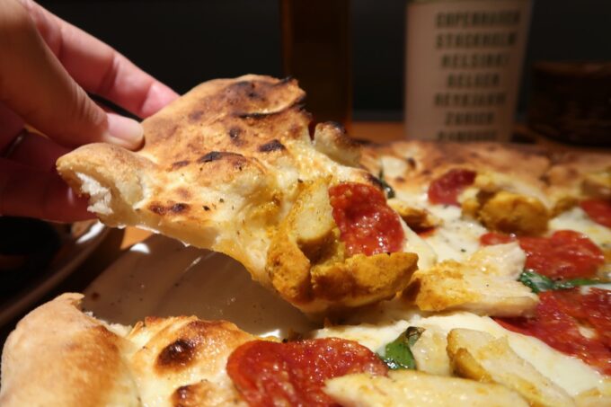「Pizzeria Bar Ariccia（ピッツエリア バール アリッチャ）」ディアボラピザを持ち上げる