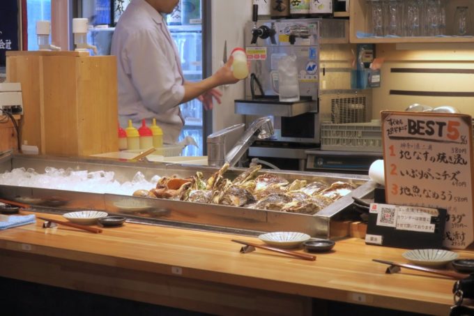 横浜・野毛「魚と酒 はなたれ 野毛一番街店」のカウンター席と氷に並べられる牡蠣
