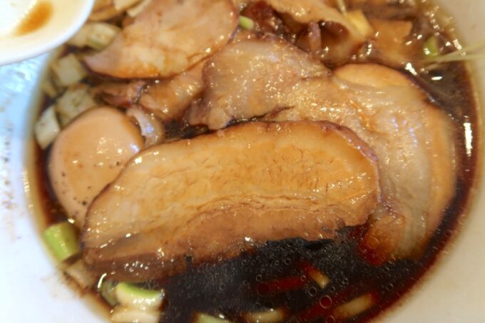 読谷村長浜「麺屋 シロサキ」焼豚麺Black（1200円）のスープに浸った三枚肉焼豚
