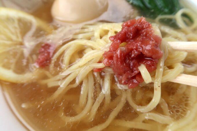 うるま市「闘牛拉麺ラブメンうるマルシェ店」冷やし塩らーめん（780円）に乗せられた刻み梅で麺がずるずると進む