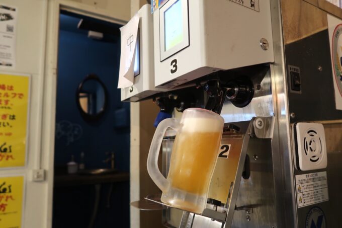 沖縄市・コザの一番街にある「セルフスタンド酒場 勝手にしやがれ」自動サーバーでビールを注ぐ