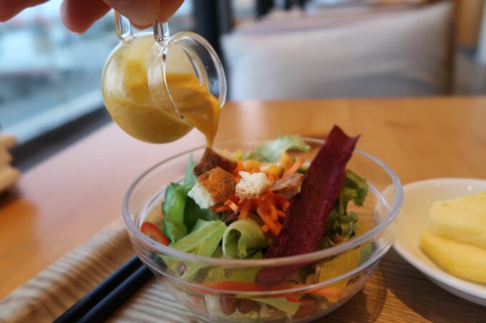 宮古島「HOTEL LOCUS（ホテルローカス）」朝食のサラダにマンゴードレッシングをかける