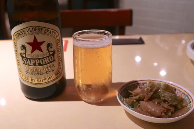 那覇市牧志「琉球餃子マニア」瓶ビールのサッポロ赤星（660円）とお通しのザーサイ（280円）