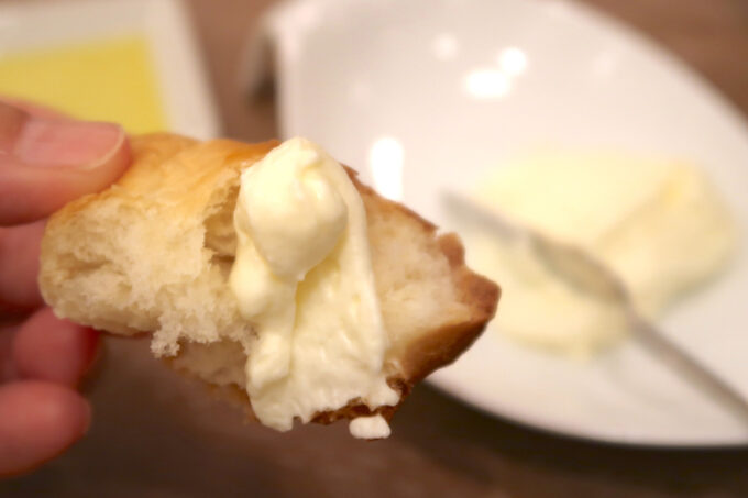 パルコシティ1階「PIER'S BAKERY サンエー浦添店」セレクトランチ（1738円）の湯種パンにクリームチーズを乗せて頬張る