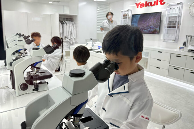 「キッザニア福岡」の科学研究所で顕微鏡を覗き込むお子サマー