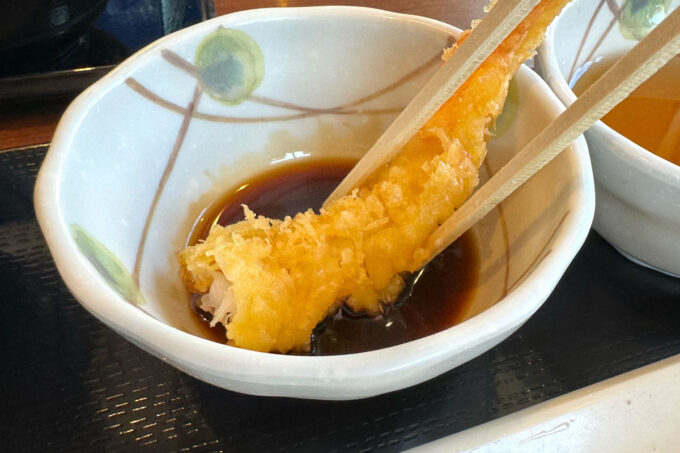 「丸亀製麺 宜野湾」カツオ出汁が香る甘めの天丼用たれに天ぷらをつけて食べる