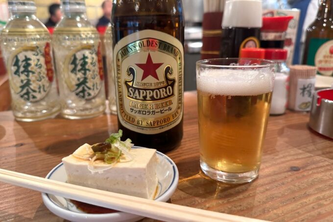 札幌市「もつ焼・煮込み いなり」瓶ビール（サッポロラガー、650円）とお通し（280円）の冷奴