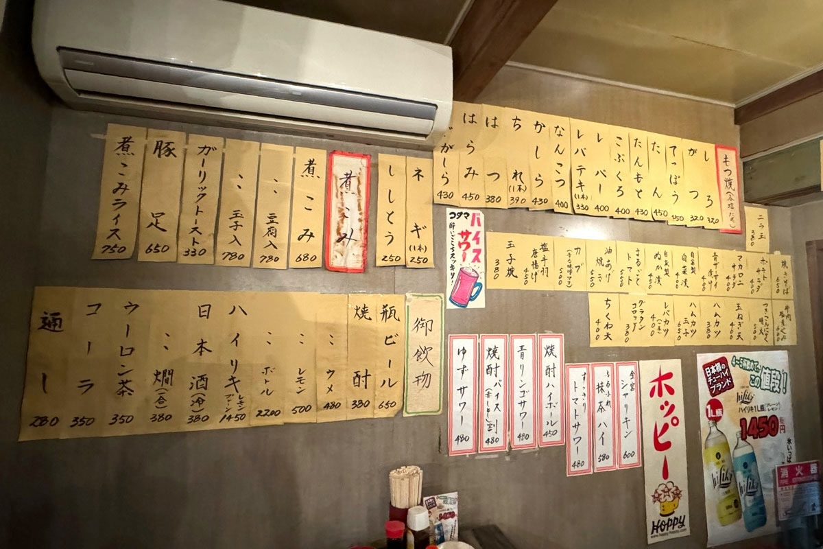 札幌市「もつ焼・煮込み いなり」壁に貼られたドリンクメニューやもつ焼きなどのメニュー