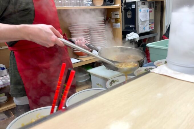 札幌・すすきの「ラーメン信月」カウンターの中で熱々のスープを注ぐ店員さんの手元