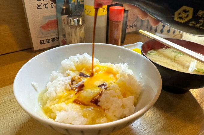 新梅田食堂街「大阪屋」朝定食の卵かけごはんに醤油を掛け回す