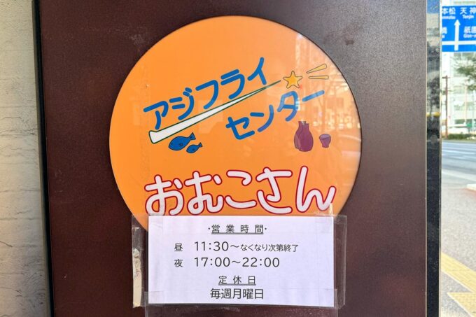 福岡市の博多駅前にある「アジフライセンター おむこさん」の看板と営業時間