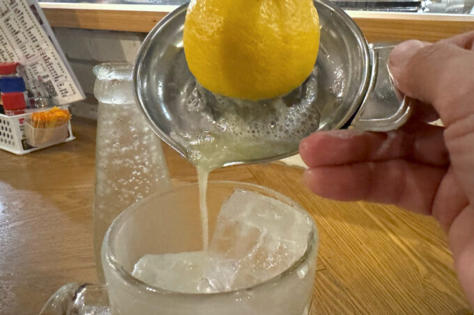 那覇市牧志「もつ焼きばん 沖縄那覇店」自分でレモン半分を絞ってグラスへ注ぐ