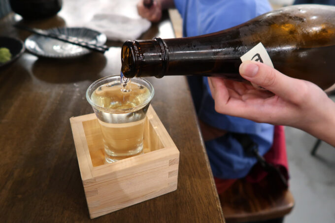 那覇市松尾「大衆キッチンたまや」せんべろのおはじきを2枚使って日本酒を注いでもらう